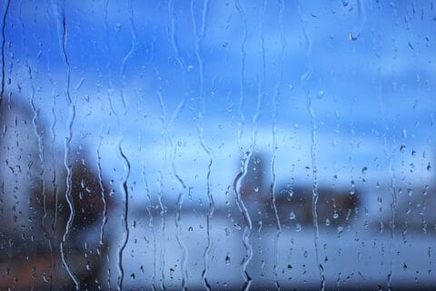 water,droplets,and,rain,streaks,on,window,glass,against,a