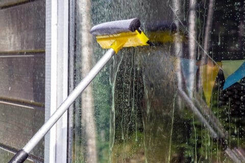 washing Windows, cleaning glasses and surfaces. yellow-white telescopic washing brush cleanly washes and wipes the Windows of the house.